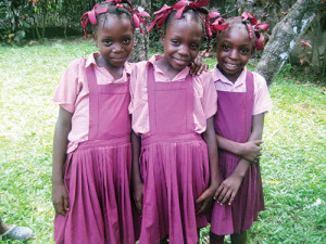 Twins and sister attend school. The uniforms are made locally and provide needed income to women.